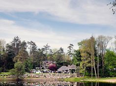 a large house sitting on top of a lush green field next to a forest filled with trees