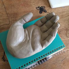 a sculpture of a hand on top of a notebook