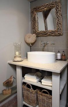 a bathroom sink sitting under a mirror next to a shelf with baskets on top of it