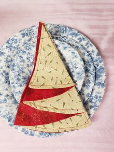 a table setting with blue and white plates, napkins and a red sailboat decoration