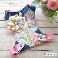 a pair of pink and blue boots sitting on top of a wooden floor next to flowers