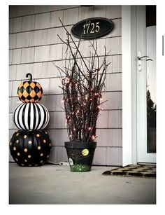 a black and white pumpkin sitting next to a potted plant on the side of a house