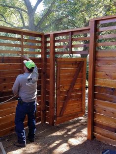 a man standing in front of a wooden gate with a green hat on his head