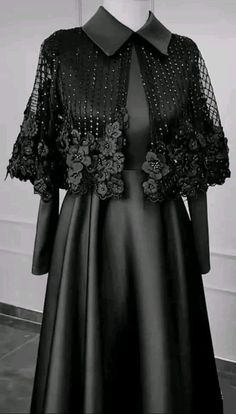 a black dress with flowers on it and a collared neckline is shown in front of a mannequin's head