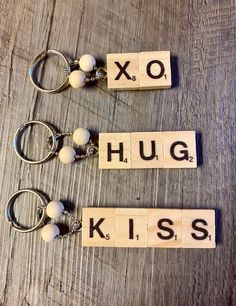 three scrabble key chains with letters spelling hugs, hugs and kisses on them