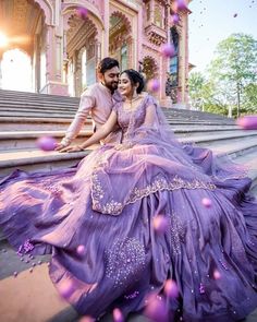 a man and woman are sitting on some steps wearing purple dresses with bubbles in the air