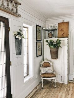 a room with white walls, wooden floors and an old chair in front of the door