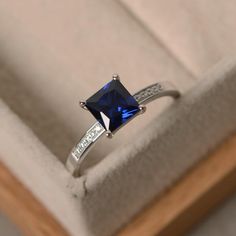 an engagement ring with a blue stone and diamond accents in a gift box on display