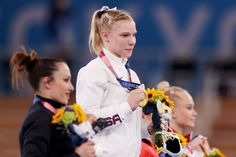 three female athletes holding their medals and flowers