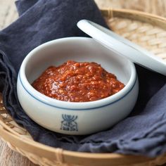 a bowl filled with sauce sitting on top of a blue napkin next to a spoon