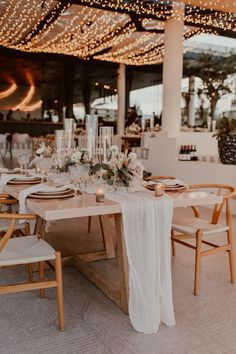 a table set up with white linens, candles and flowers for a wedding reception