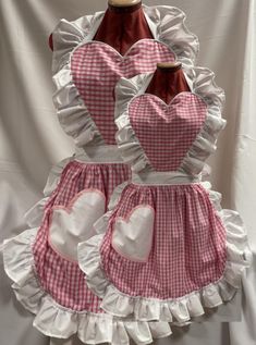 two aprons with hearts on them are sitting on a mannequin headdress