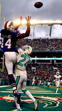 two football players are jumping up to catch the ball