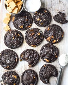 chocolate cookies with orange zest are on a baking sheet next to a bowl of butter and a spoon