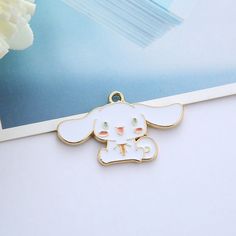 a cute little dog charm sitting on top of a table next to a white flower