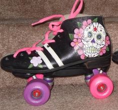 a pair of roller skates decorated with sugar skull and pink wheels on a couch