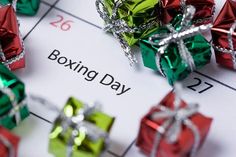 the word boxing day written on a calendar surrounded by small gift wrapped in ribbon and bows