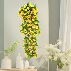 yellow flowers are hanging from the side of a wall in a room with white vases