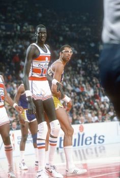 three basketball players standing on the court in front of an audience at a sporting event