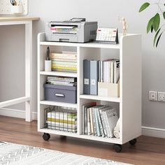 a white book shelf filled with lots of books and office supplies on top of a hard wood floor