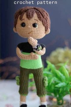 a crocheted boy holding a cat on top of a table next to plants