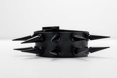 comfortable design. It measures 10 inches in length and 1.5 inches in width, made from soft black leather with adjustable metal buckle, adorned with 10 glossy black alloy metal studs that stick out 1 inch. Black Edgy Wristband With Studs, Punk Leather Bracelet With Studs, Punk Style Studded Leather Bracelet, Edgy Leather Bracelets With Studs, Black Rocker Bracelets With Rivets, Black Rocker Bracelet With Studs, Black Rivet Rocker Bracelets, Gothic Leather Bracelet With Spikes For Party, Black Leather Bracelet With Studs For Rock Style