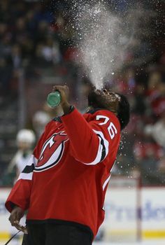 a man in red jersey spraying water on his face at an ice hockey game,