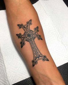 a person with a tattoo on their arm that has a cross in the middle of it