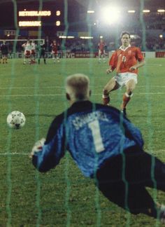 two men playing soccer on a field at night with the ball in front of them