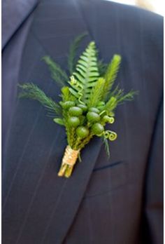 a man wearing a suit and tie with green flowers on it's lapel