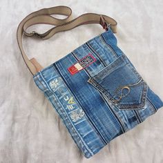 a purse made out of old jeans on a white sheet with a brown belt strap