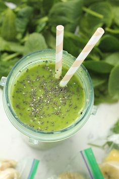 two straws sticking out of a green smoothie