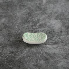 a green and white plate sitting on top of a gray table next to a cup