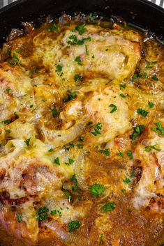 a pan filled with meat and cheese covered in parsley