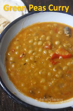 a white bowl filled with beans and carrots on top of a wooden table next to bread