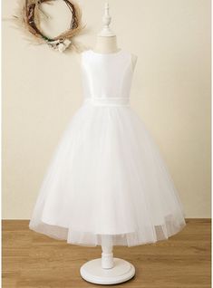 a white dress on a mannequin stand next to a wreath