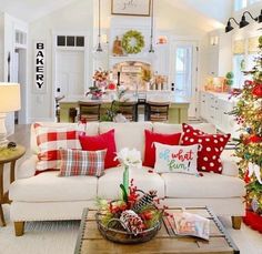 the living room is decorated for christmas with red and white pillows on the couches