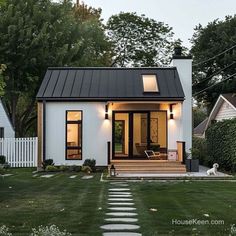 a small white house sitting on top of a lush green field