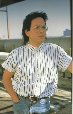 a man with glasses standing in front of an airplane and looking off to the side