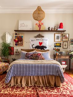 a bed room with a neatly made bed and lots of pictures on the wall above it