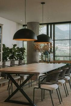 a dining room table and chairs in front of large windows