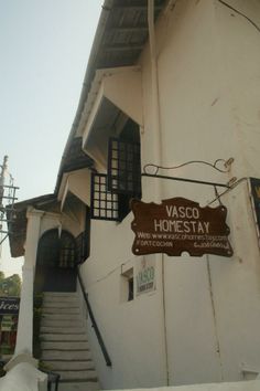 a sign on the side of a building that says vasco homestay with stairs leading up to it