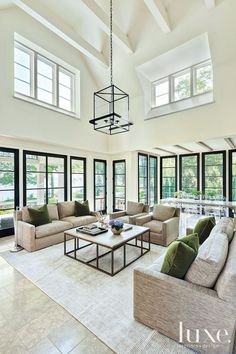 a large living room with high ceilings and lots of windows on the ceiling is filled with furniture