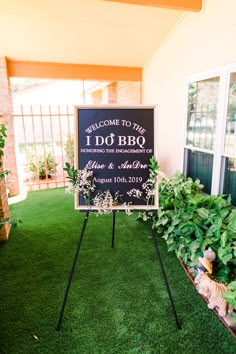 a welcome sign sitting on top of a lush green field next to a small garden