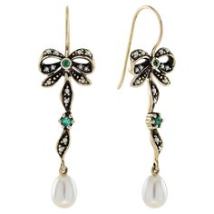 These earrings boast a vintage-inspired design adorned with delicate gold bows. Enhanced with sparkling milgrain details, the pearls gracefully align along the bow tie, culminating in a sizable, elegant white drop at the base to imbue movement and allure. Centrally positioned round green amethysts adorn both the bow tile and the bow knot, ensuring these earrings mesmerize the beholder with their timeless allure, reminiscent of a bygone era, with every graceful step.. CHARACTERISTICS Status: Made Blue Emerald, Earring Box, Emerald Color, Bow Knot, Bygone Era, Yellow Gold Earring, Vintage Inspired Design, Green Amethyst, Natural Pearls