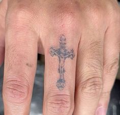 a hand with a cross tattoo on it