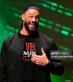 the rock giving a thumbs up on stage at an event with green lights behind him