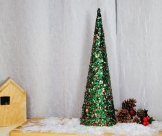 a small green christmas tree sitting on top of a wooden table next to a birdhouse