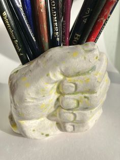 a ceramic hand holding pencils in it's holder