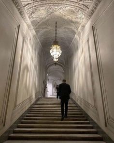 a man is walking down the stairs in an old building with chandelier hanging from the ceiling